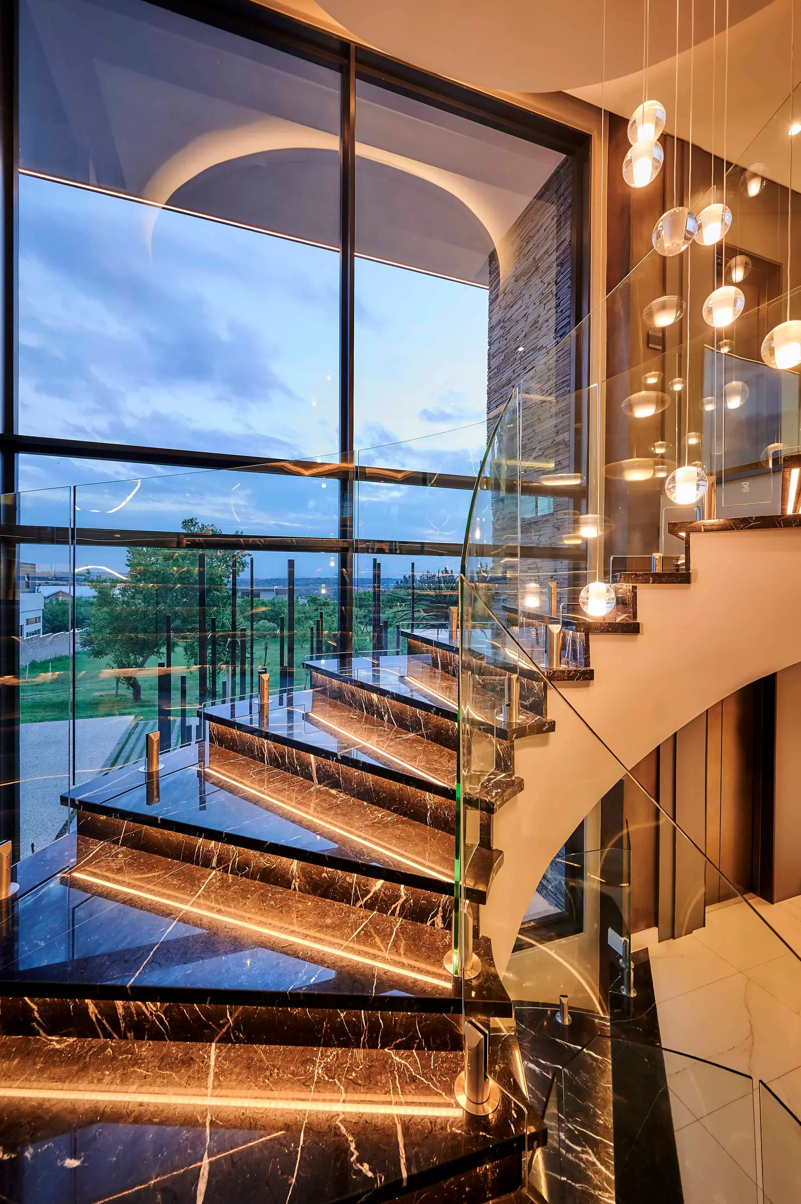 Modern staircase with glass balustrade and hanging light fixture designed by Interior Designer Johannesburg.