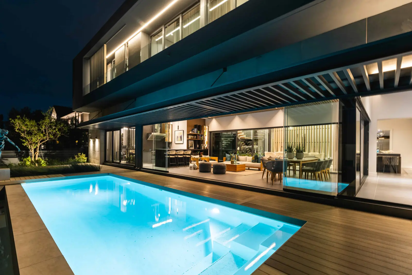 Contemporary pool area with deck lighting and architectural overhang, Steyn City residence – Renovatio Interior Design Johannesburg.