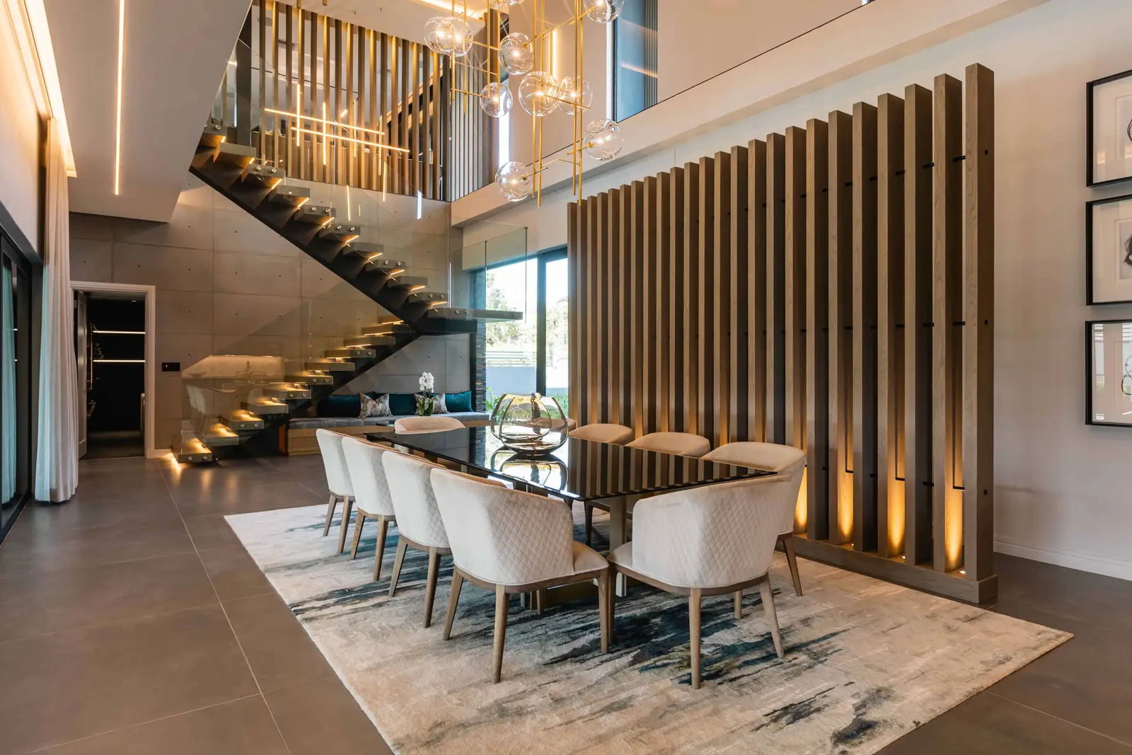 Sophisticated dining hall with sculptural staircase and designer furniture in Steyn City residence, Johannesburg interior designer.