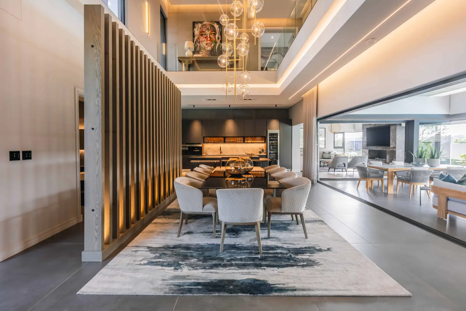 Sculptural staircase, dining room and hallway with natural light in a Steyn City residence, Johannesburg interior design.