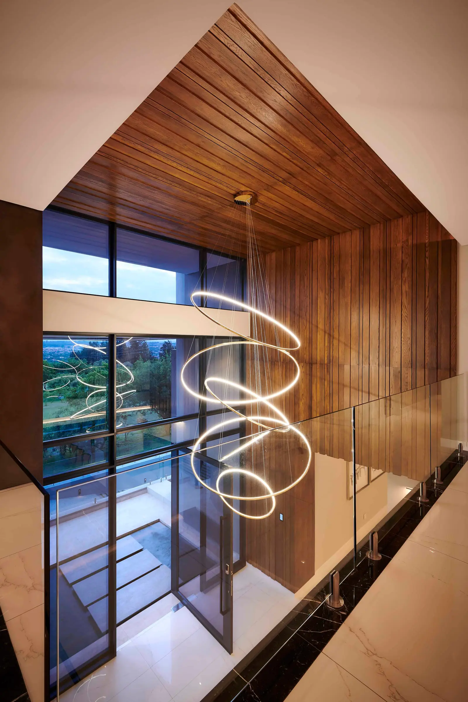 Modern entrance hall with wooden ceiling detail, statement chandelier and large windows by Interior Designer Johannesburg.