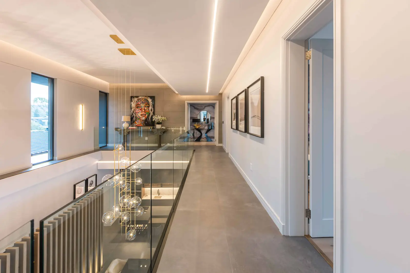 Upper landing with glass balustrade overlooking living area, Steyn City – Johannesburg interior designer.