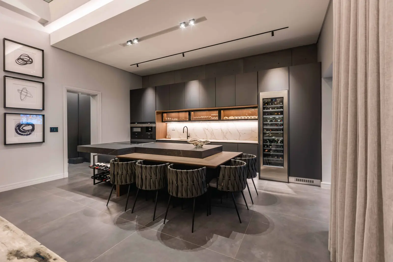 Formal dining room with sculpted lighting and kitchen backdrop in Steyn City – Johannesburg interior designer.