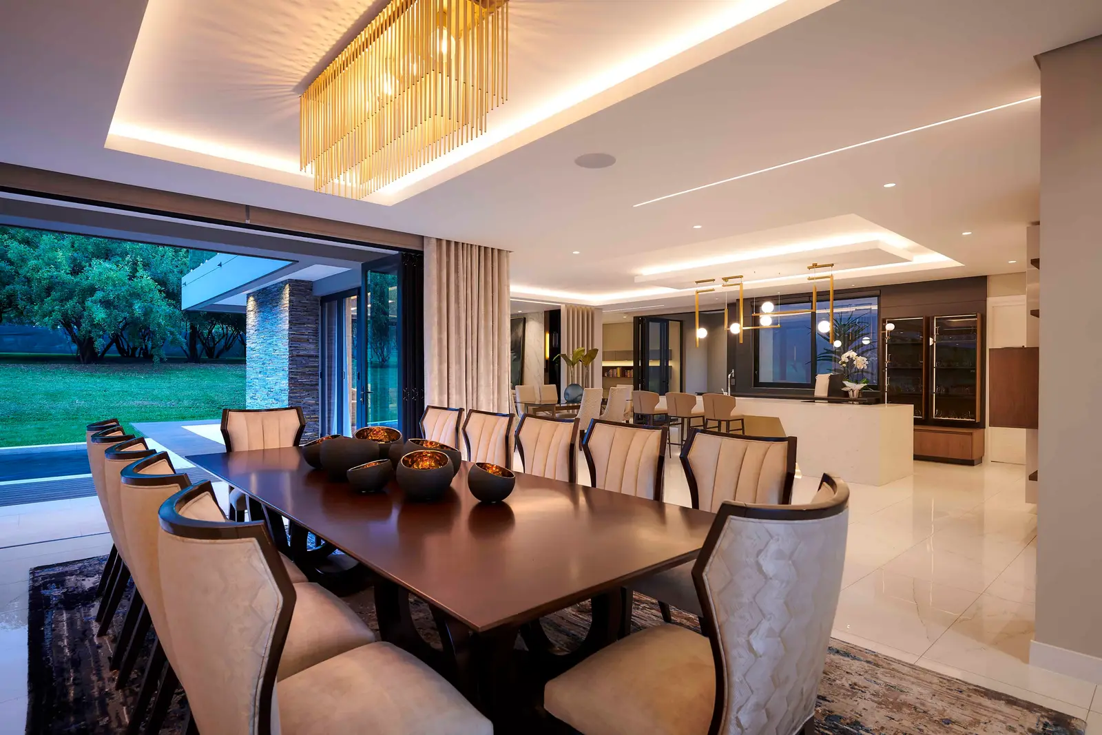 Elegant dining room with a long wooden table, plush chairs and a modern chandelier, designed by Interior Designer Johannesburg.