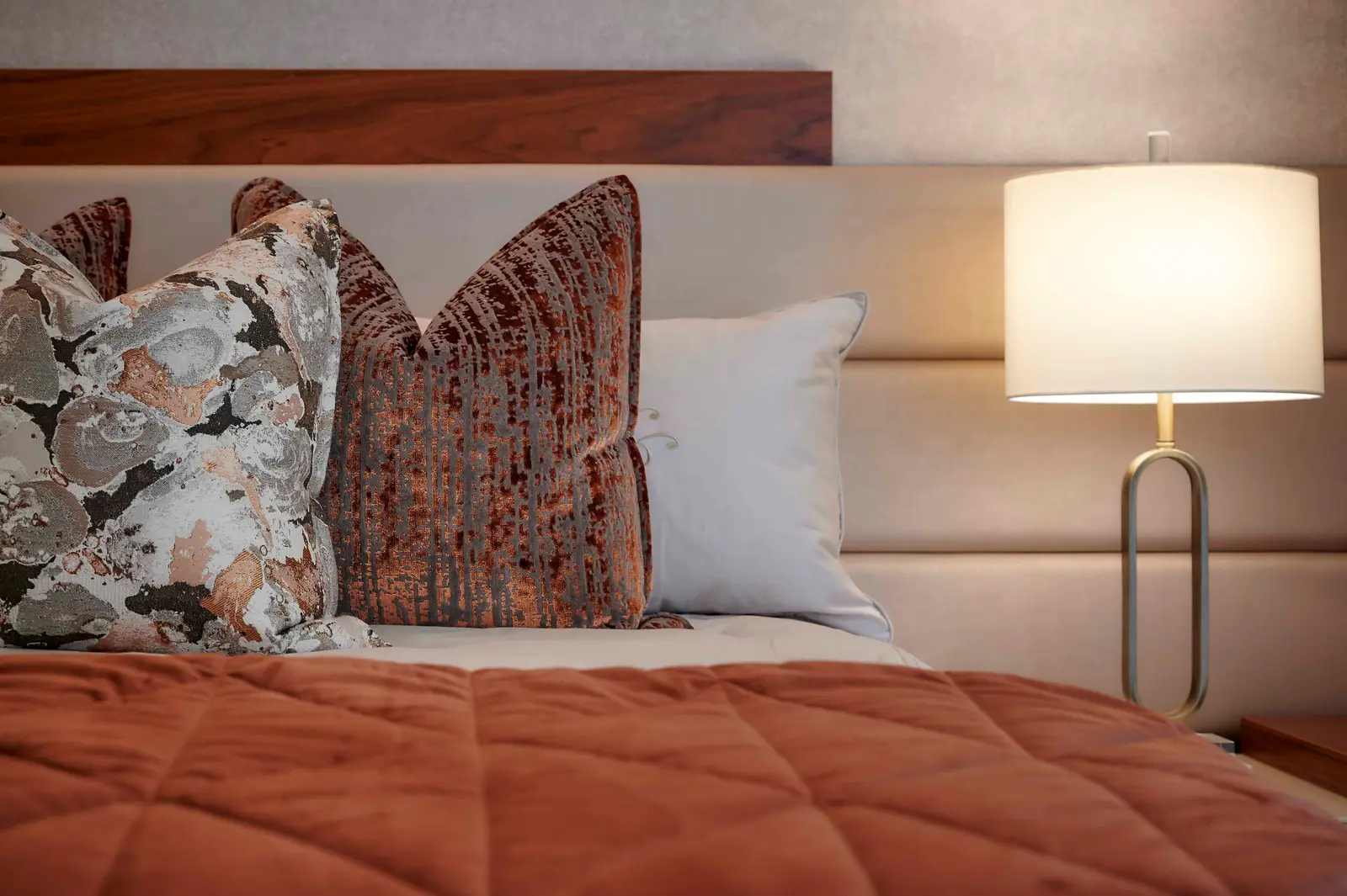 Cozy bedroom scene with decorative pillows, textured bedding and a bedside lamp styled by Interior Designer Johannesburg.