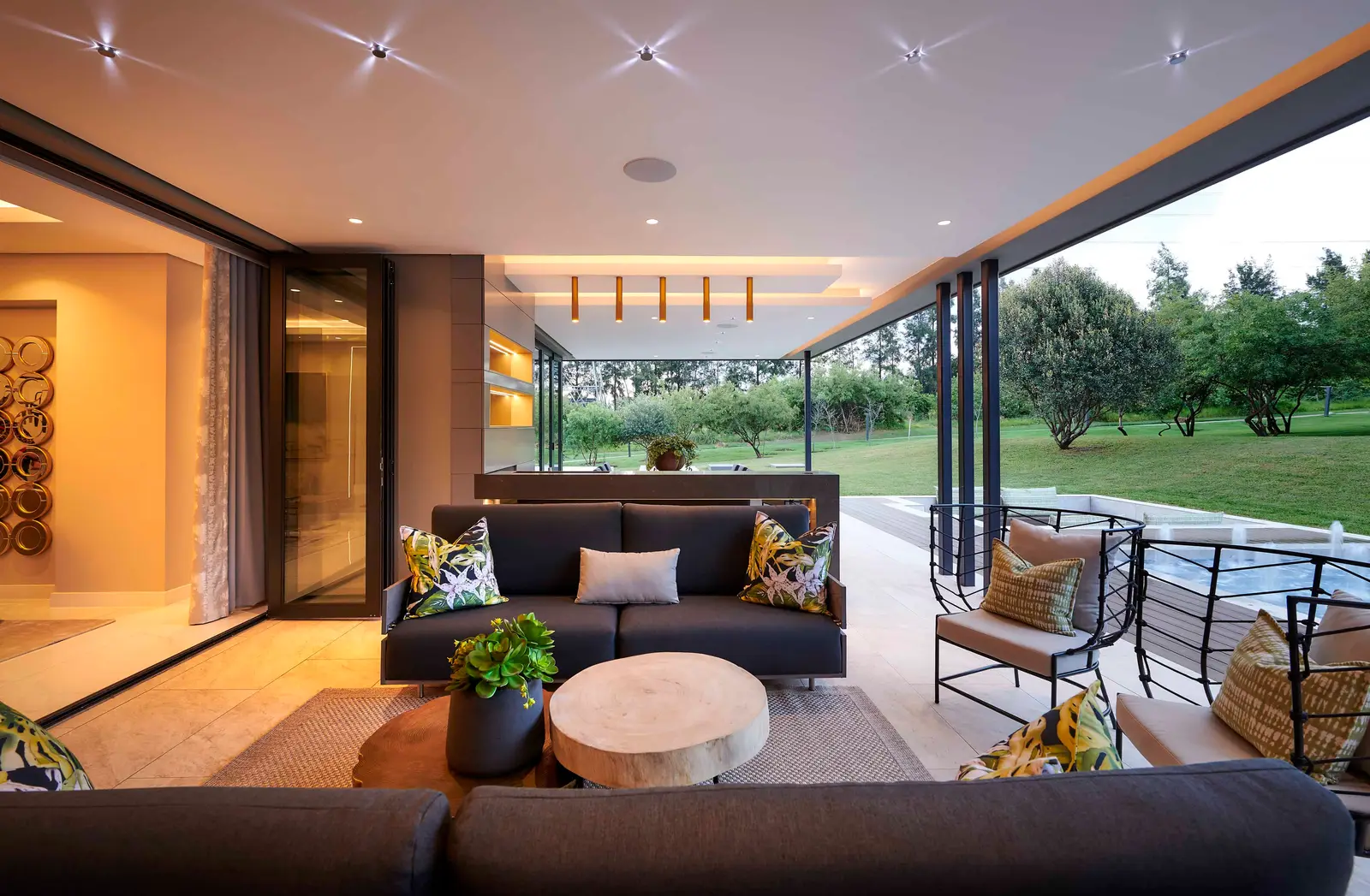 Stylish outdoor patio with seating area overlooking a pool and lush greenery, curated by Interior Designer Johannesburg.